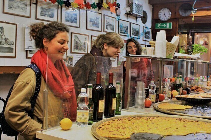 Un puesto de comida con una gran masa plana, botellas de aceite de oliva y un limón en la barra. 2