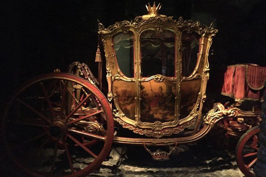 A vintage carriage with ornate decorations and large red wheels. 4