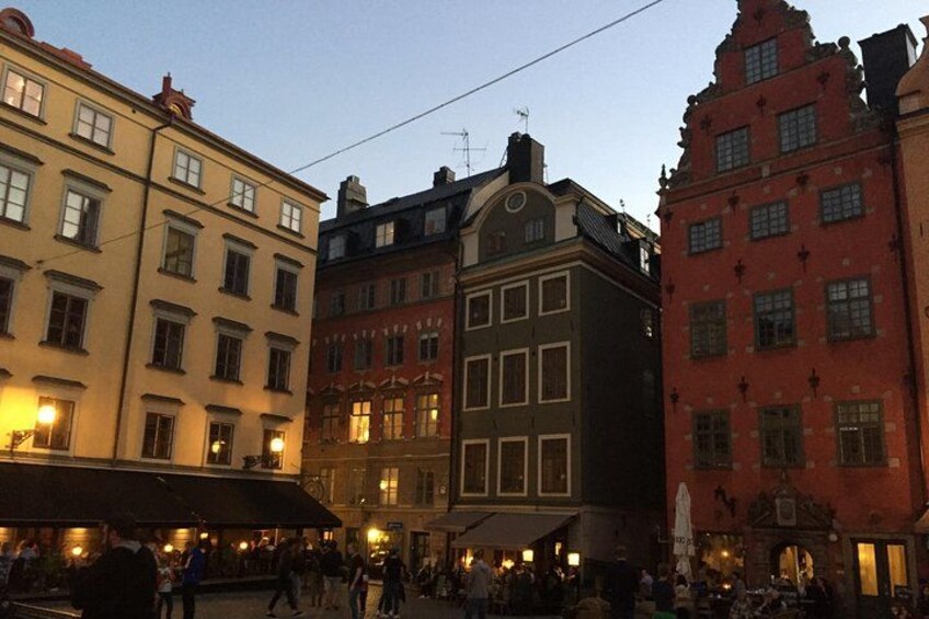 A street scene with historic buildings, a covered walkway, and people walking. 1