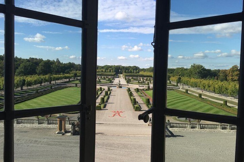 A formal garden with a central pathway, symmetrical landscaping, and a distant view of trees and sky. 5