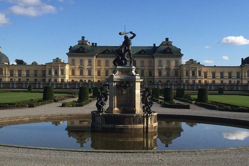 A classical fountain with statues in front of a large, ornate building with a green roof. 4