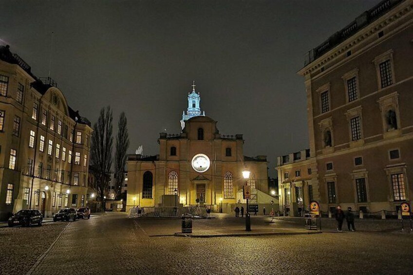 A historic building with a clock tower at night, surrounded by other buildings. 2