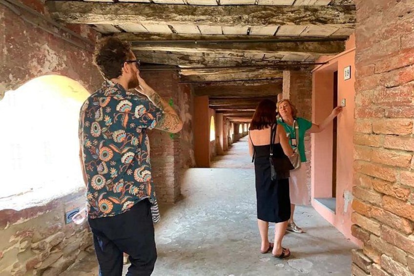 A corridor with brick walls and a tiled floor, leading to a door marked with the number 19. 5