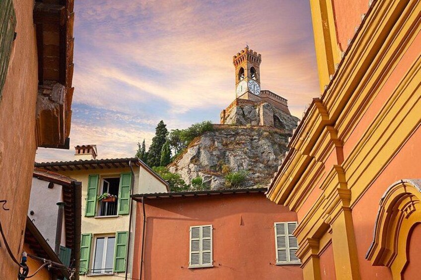 A historic tower with a clock, surrounded by colorful buildings with shutters. 1