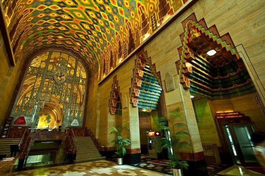 A grand interior with ornate ceiling patterns, a large arched window, and a staircase. 3