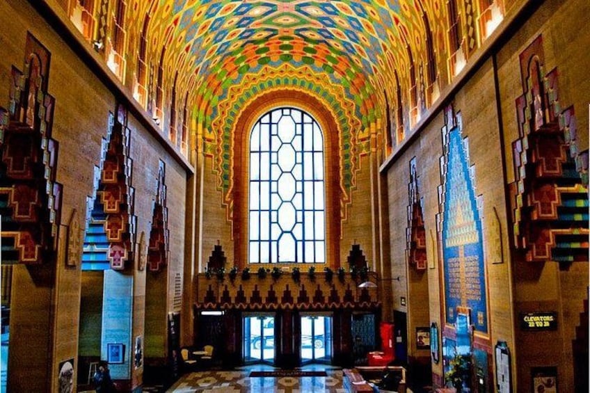 Un gran salón con un amplio ventanal de arco, intrincados diseños geométricos en las paredes y un suelo estampado. 2