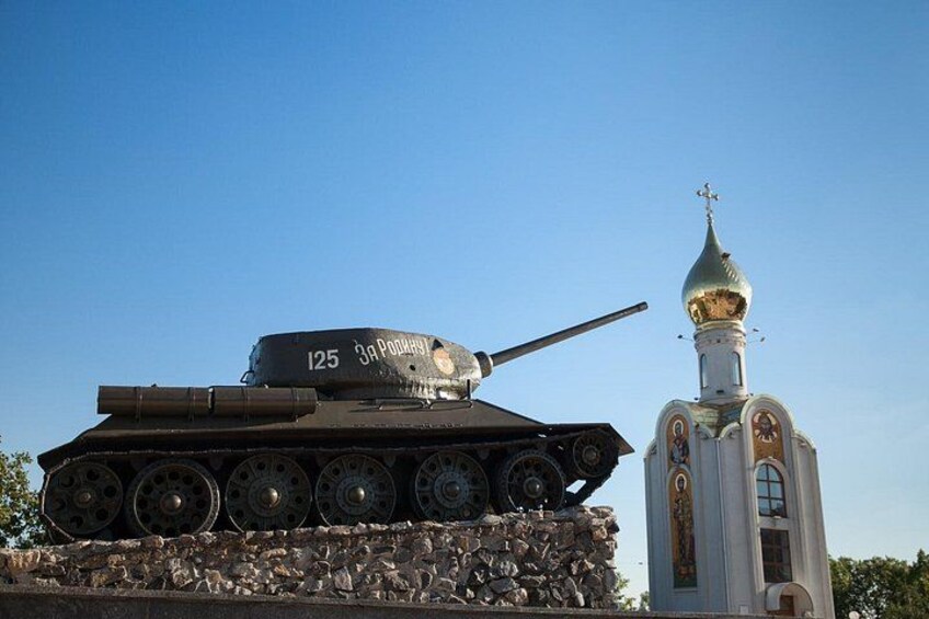 Un tanque militar con el número 125, una iglesia con cúpula dorada y un cielo azul despejado. 5
