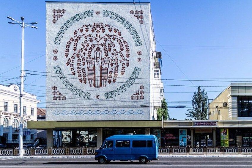 Una camioneta azul estacionada frente a un edificio con un gran mural. 4