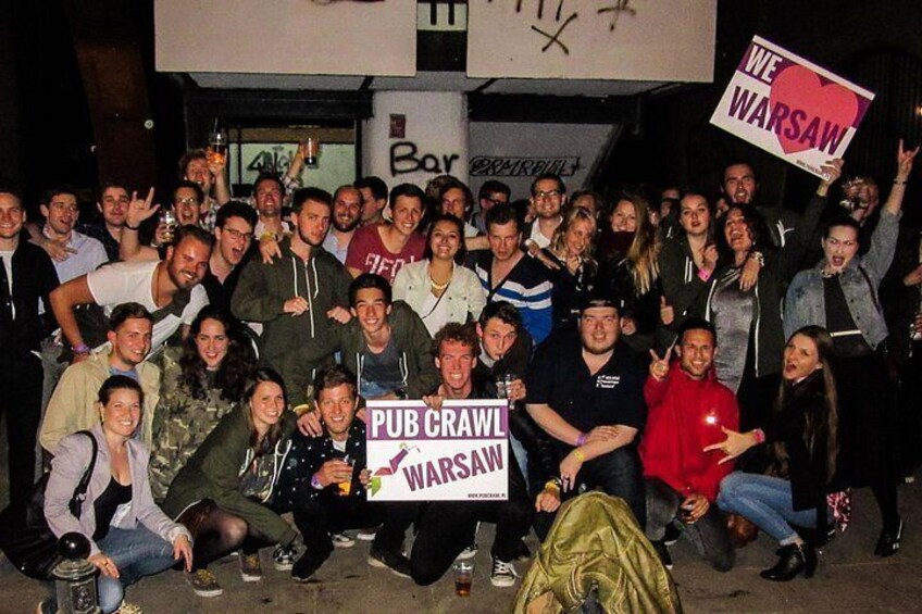 Un grupo de personas sosteniendo pancartas que dicen 'PUB CRAWL WARSAW' y 'AMAMOS VARSOVIA'. 2