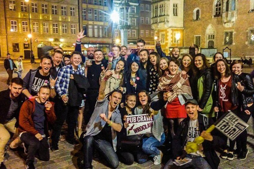 A group of people posing for a photo on a city street at night. 1