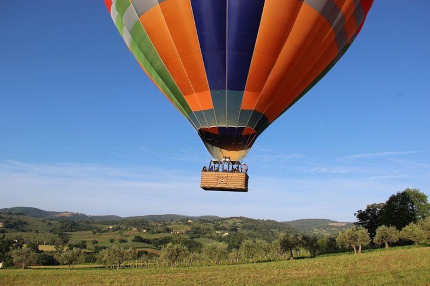A hot air balloon with a basket over a hilly landscape. 5