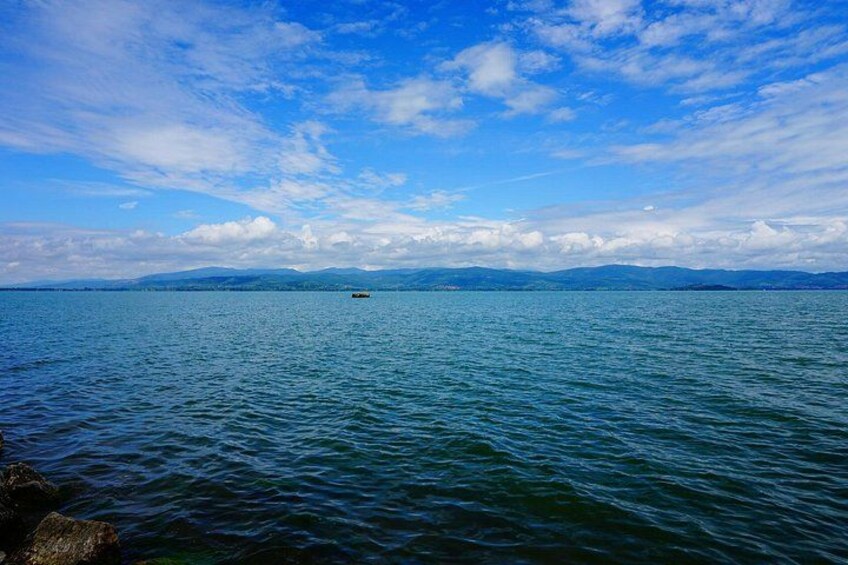 A calm sea with a small boat in the distance and a clear sky. 4