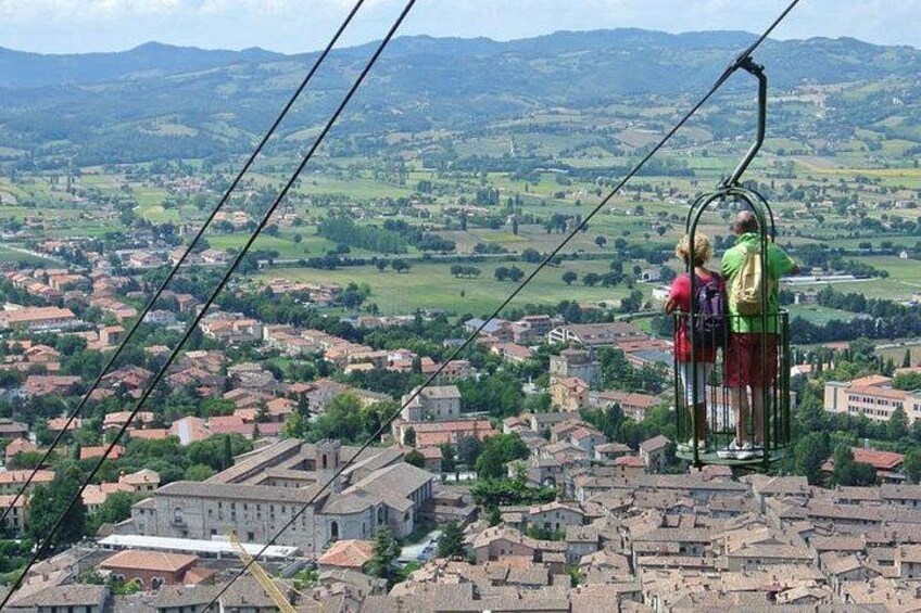 A cable car with passengers overlooking a town and countryside. 1