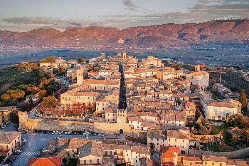 A town with a central square, historic buildings, and a mountainous backdrop. 4