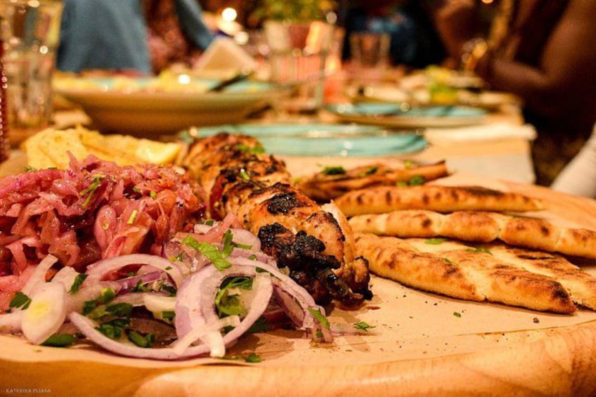 A table with grilled chicken, sliced onions, and flatbread. 5