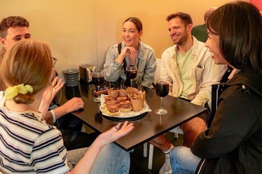A group of people sitting around a table with food and drinks. 4