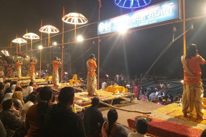 A nighttime outdoor event with a stage, people, and a large crowd. 2