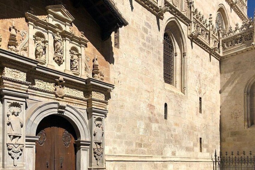 A historic building with ornate stone carvings, a large wooden door, and a window with metal bars. 4