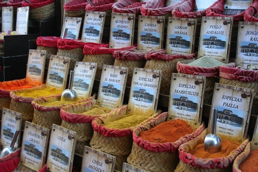 A display of various spices in woven baskets with labels. 2