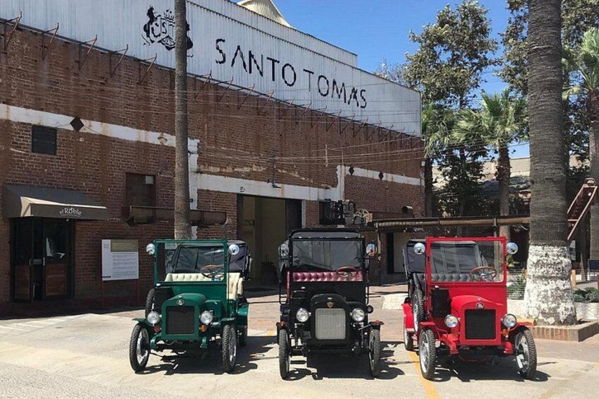 Drei Oldtimer-Jeeps parken vor einem Gebäude mit der Aufschrift 'SANTO TOMAS'. 1