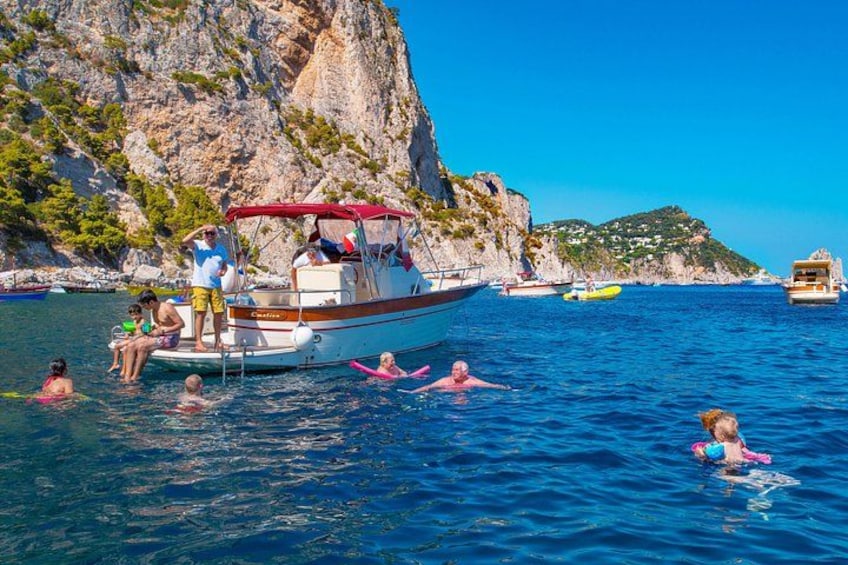 Una barca con persone su una costa rocciosa, acque calme e cielo sereno. 1