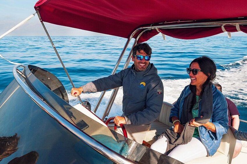 A boat with two people on board, a red canopy, and the ocean in the background. 2