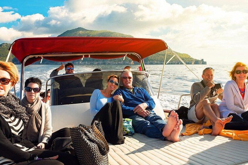 A group of people on a boat with a red canopy, sitting on a wooden deck. 5