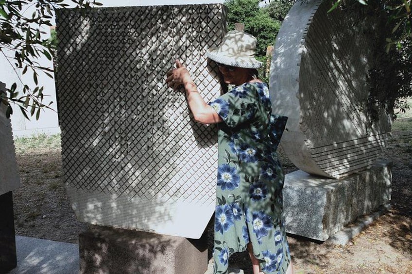 Una persona con vestido y sombrero floral interactúa con una gran estructura metálica al aire libre. 2