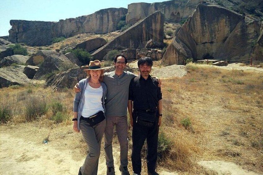 Three people standing on a dirt path with rocky cliffs in the background. 2