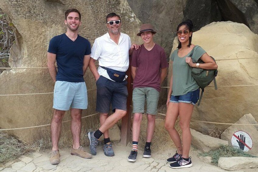 A group of people standing in front of a rocky cliff with a rope barrier. 1