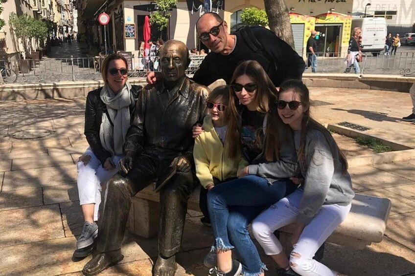 En gruppe mennesker poserer ved en statue i et bymiljø. 3