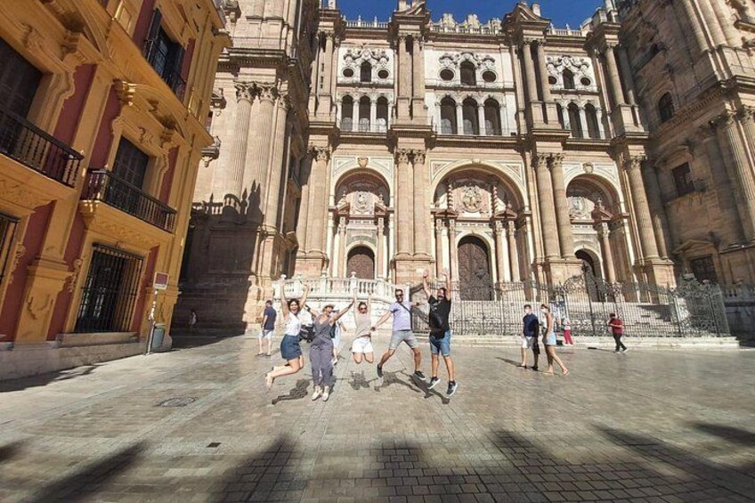 A historic building with ornate architecture, a paved plaza, and people walking. 2