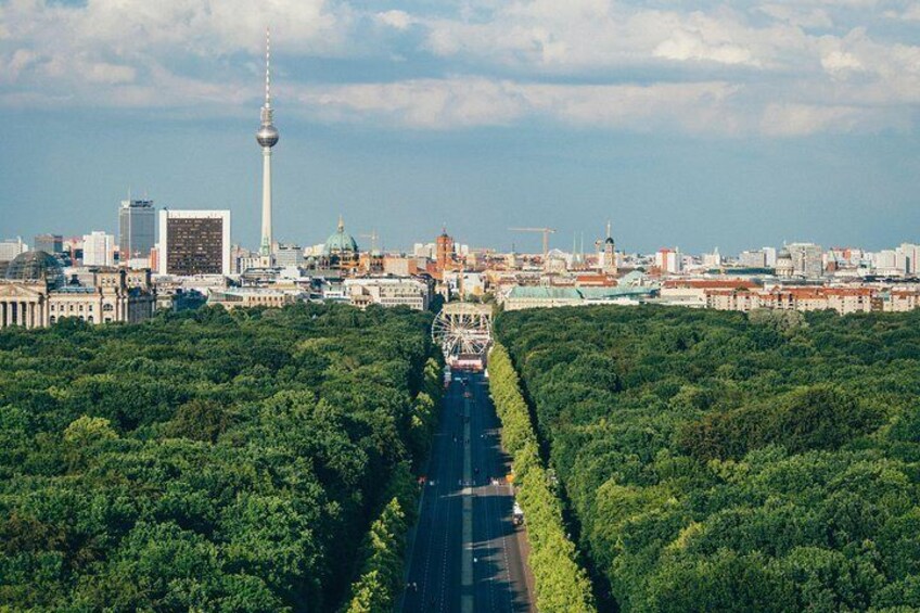 Un paisaje urbano con una torre destacada, amplias zonas verdes y un cielo despejado. 2