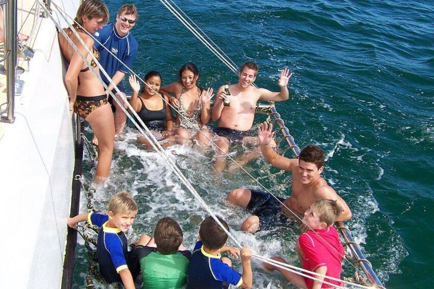A group of people on a boat with water splashing around them. 3