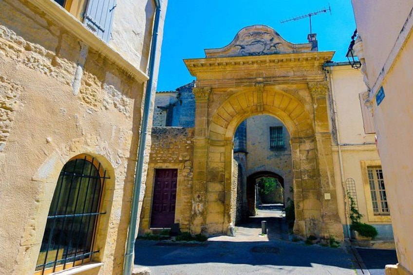 Una stretta via con un arco in pietra, una porta rossa e una piccola scalinata che conduce a un edificio. 4