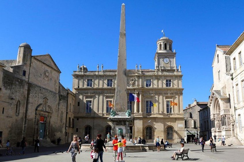 Una plaza histórica con un obelisco destacado, una torre de reloj y arquitectura clásica. 2