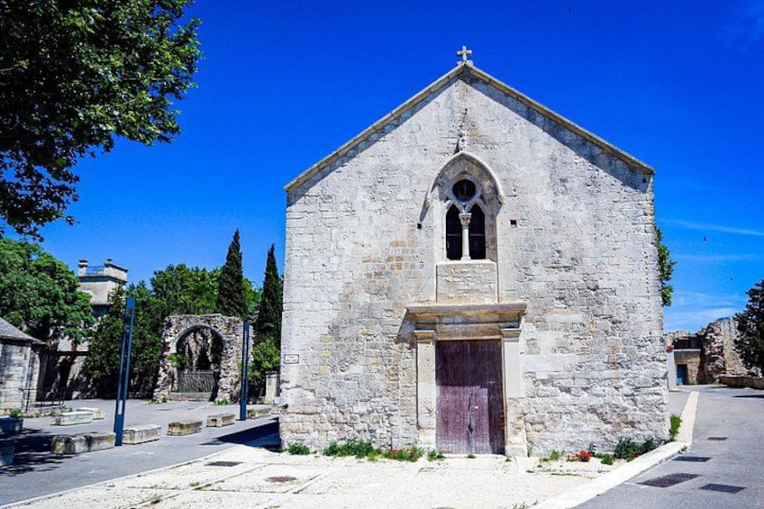 Una chiesa in pietra con una croce sulla torre, una porta in legno e un cielo azzurro intenso. 5