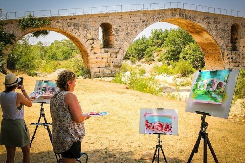A stone bridge, two artists painting, and a natural landscape. 4