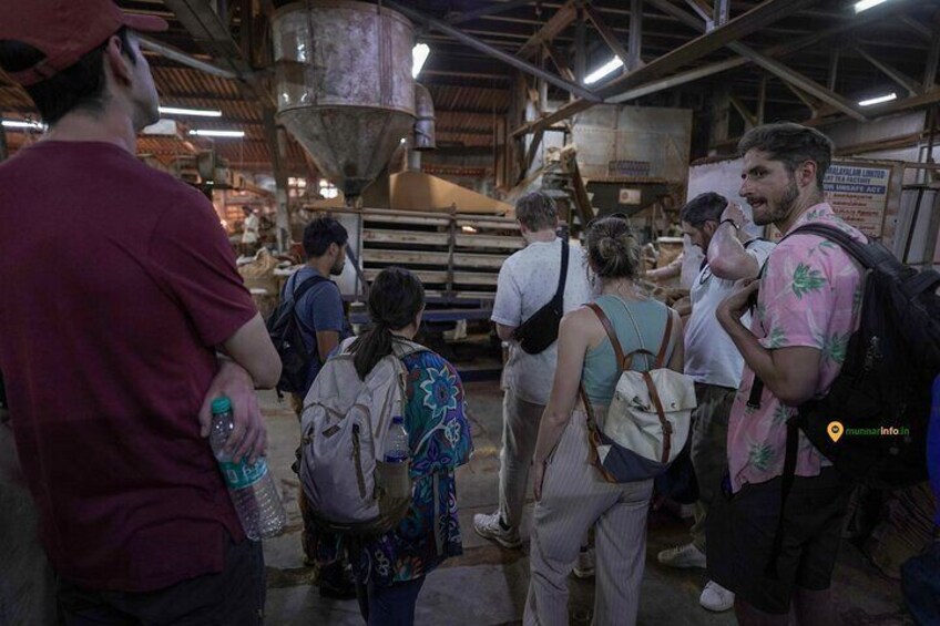A group of people in an industrial setting with machinery and metal structures. 3