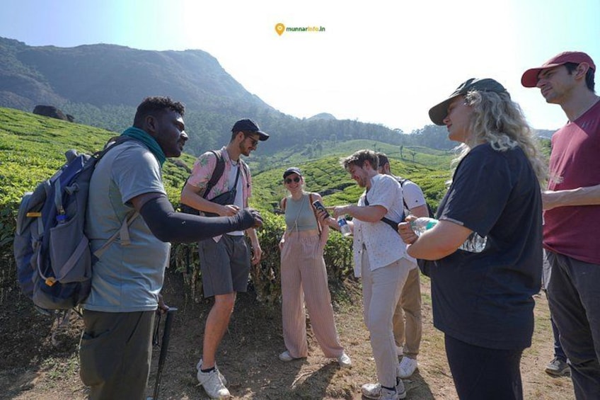 A group of people hiking in a mountainous area with lush greenery and hills in the background. 1