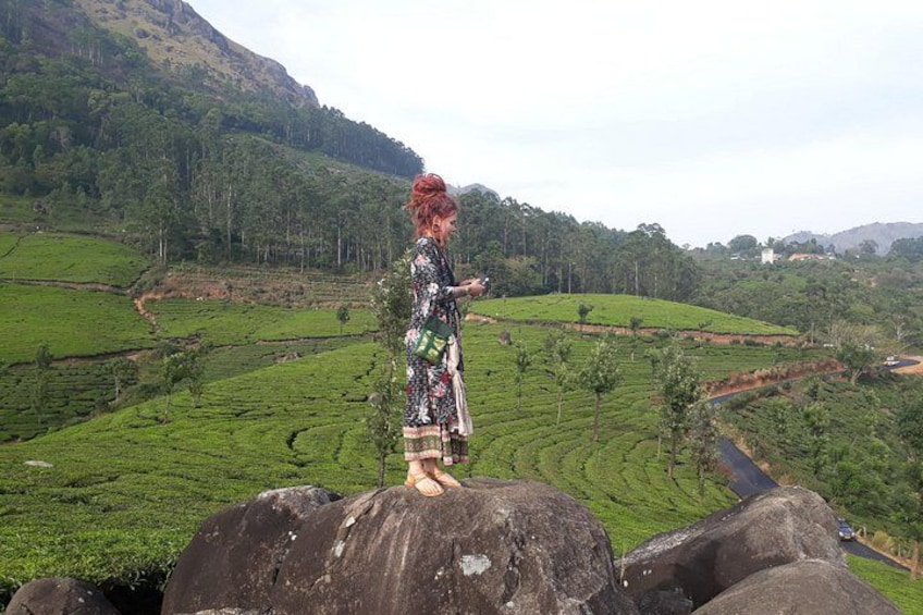 A person standing on a rock with a lush green landscape in the background. 4