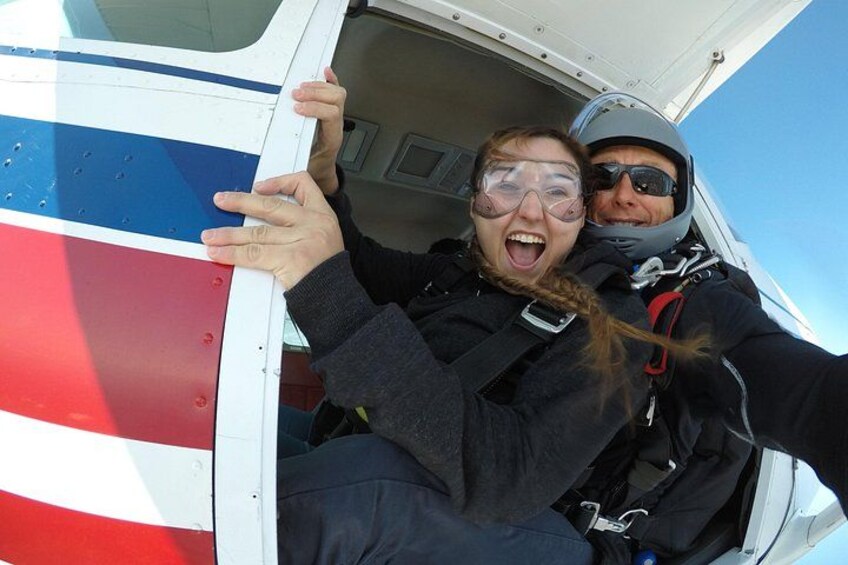 Two people in a helicopter, one holding the door. 3