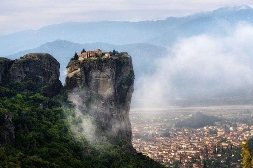Un paysage urbain dominé par une formation rocheuse imposante et un monastère situé au sommet. 1