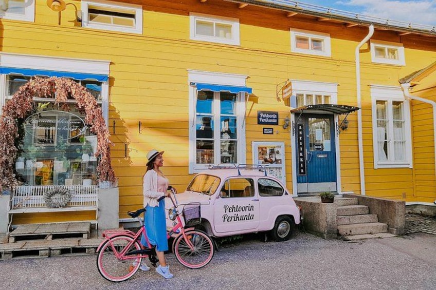 A yellow building with a pink bicycle and a pink car parked in front. 5