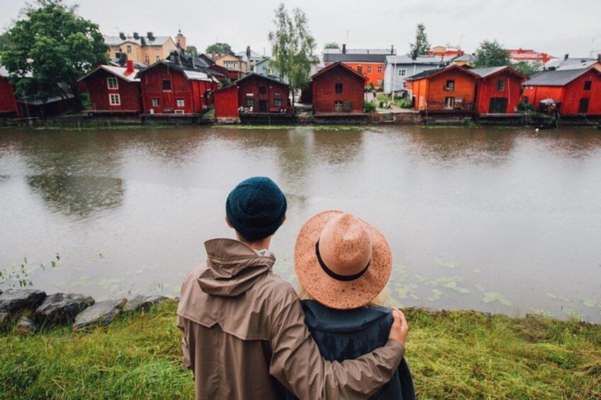 Two people standing by a lake with red houses in the background. 4