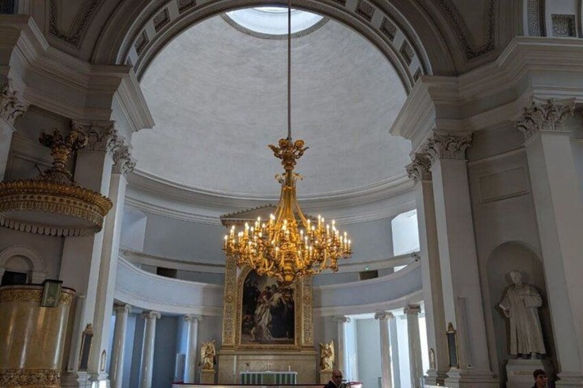 Un interior ornamentado con un gran candelabro, columnas y estatuas clásicas. 5