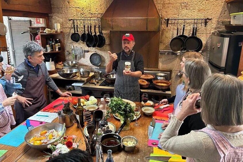 Una clase de cocina con participantes y un chef en una cocina rústica. 1