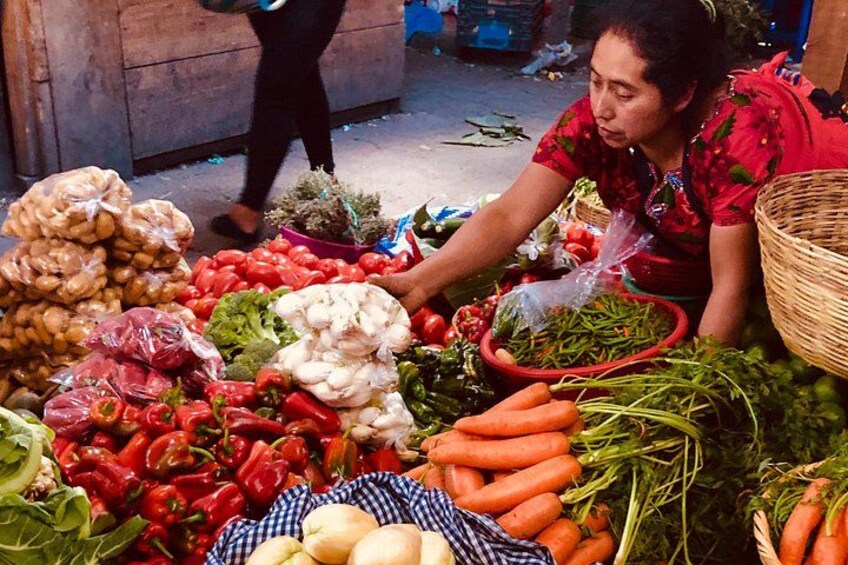 Un étal de marché où sont exposés divers légumes, comme des carottes, des poivrons et des brocolis. 3