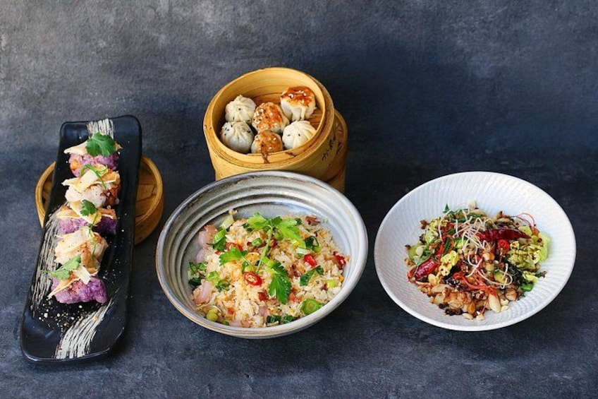 Una variedad de platos asiáticos, como dumplings, un rollo de sushi y dos ensaladas. 5