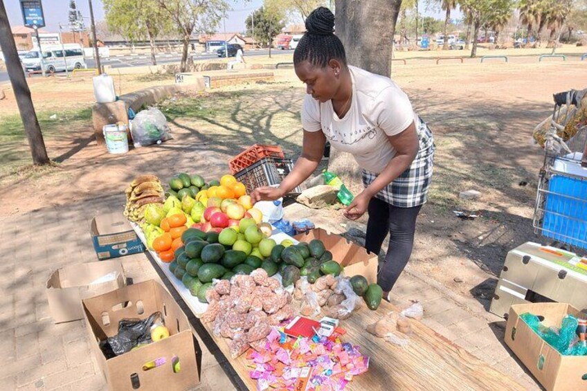 Une personne qui dispose des fruits et des légumes sur un étal dans un marché en plein air. 2